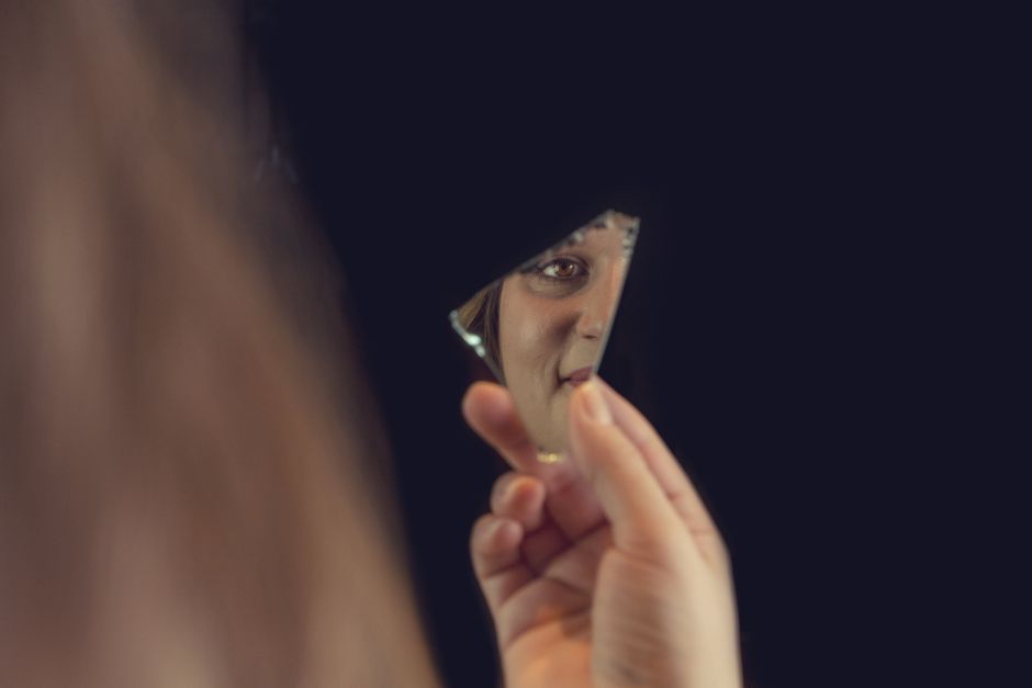 Visage reflété dans un éclat de miroir brisé, évoquant la fragmentation de l'expérience de soi